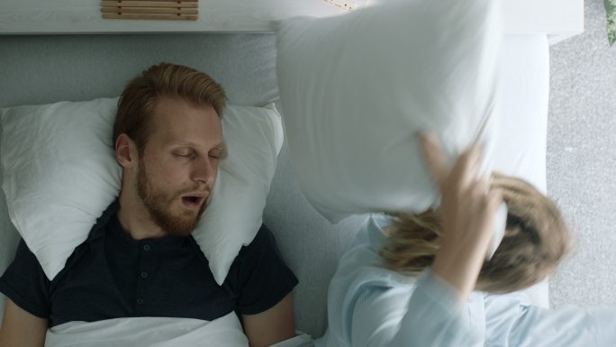 男人打呼噜，妻子用枕头捂着头
