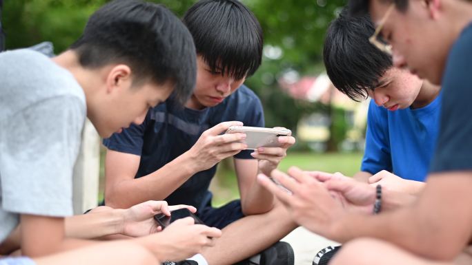 一群少年放学后在篮球场上玩手机游戏