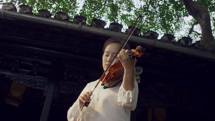 女孩在古老的院子里拉小提琴