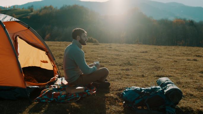 在山上露营时喝咖啡的男人
