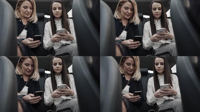 两位女士在后座使用智能手机