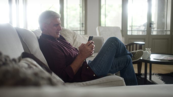 男子在家沙发上使用手机