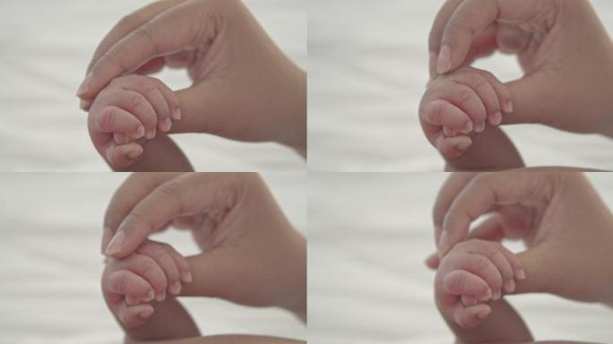 婴儿紧握着母亲的手指。