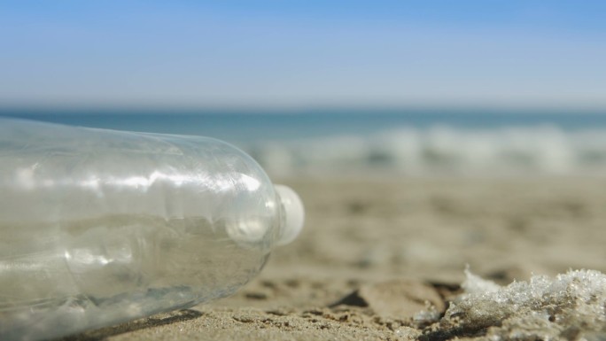 海滩背景中的巨浪沙中的水瓶
