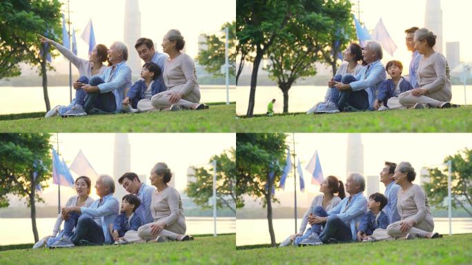 三代人家庭坐在城市公园的草地上放松