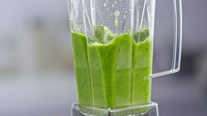 绿色冰沙在搅拌罐中旋转