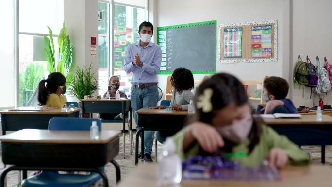 戴口罩的男教师在课堂上对学生讲话