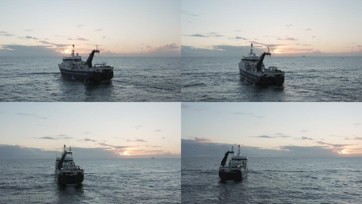 一艘拖网渔船在日落时横渡海洋