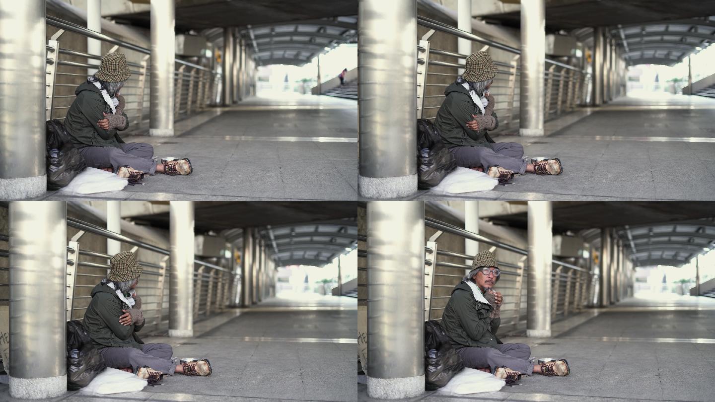 坐在人行道上的无家可归的老人。