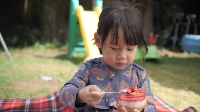 小女孩在自家花园吃奶酪蛋糕