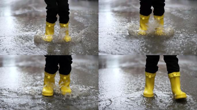 穿着黄色橡胶靴的孩子在水坑里跳跃