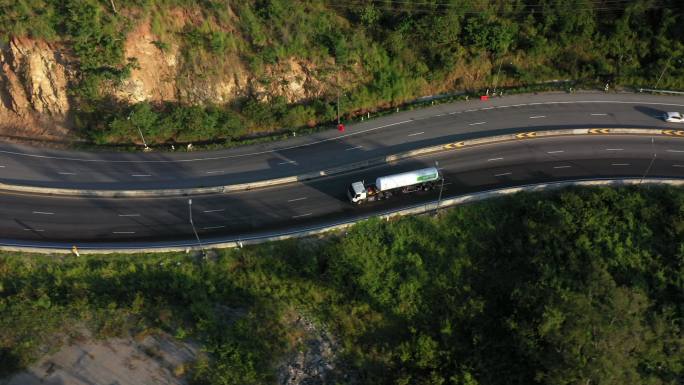 集装箱卡车在蜿蜒道路上行驶的跟踪拍摄