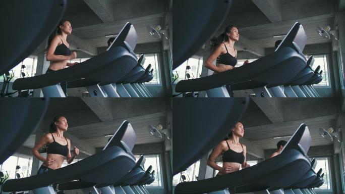 乐观的女性在健身房的跑步机上锻炼