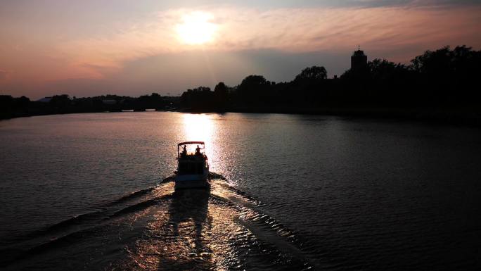 河上一艘游艇迎着夕阳驶向远方