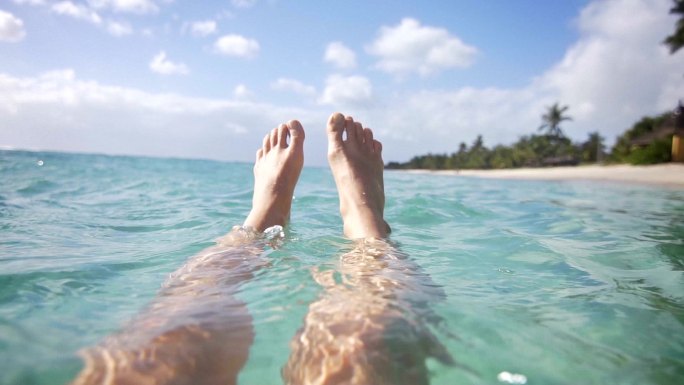 女人在海洋中放松，双脚漂浮在水中