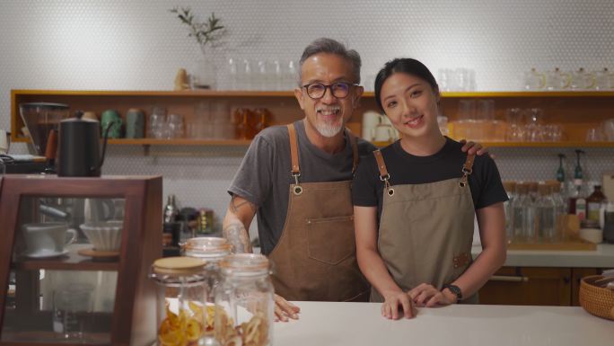 咖啡馆老板和她的女儿在咖啡馆柜台微笑着