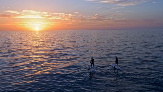 两个人划桨地平线波浪-水桨板