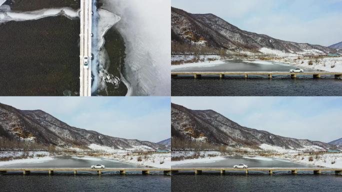 航拍大雪天田地里的桥上驶过一台汽车
