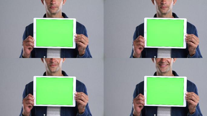 男子拿着一个绿色屏幕的数字平板
