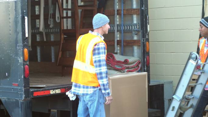两名工人正在把大箱子装上运货卡车