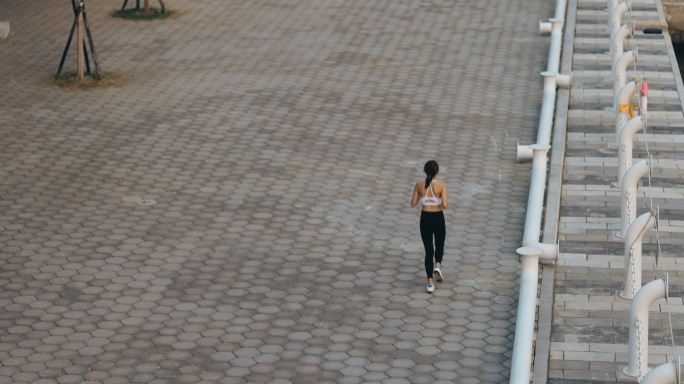 在城市公园路慢跑的年轻女子