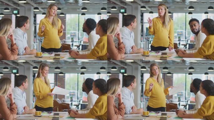 怀孕的女商人向围坐在桌子旁的同事做演讲
