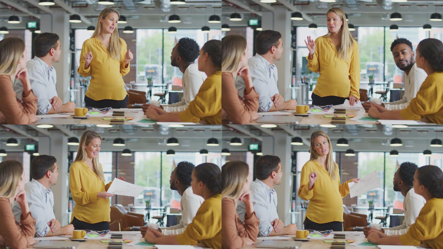 怀孕的女商人向围坐在桌子旁的同事做演讲