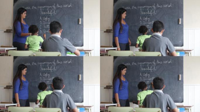 女老师把粉笔递给小女孩回答黑板上的问题