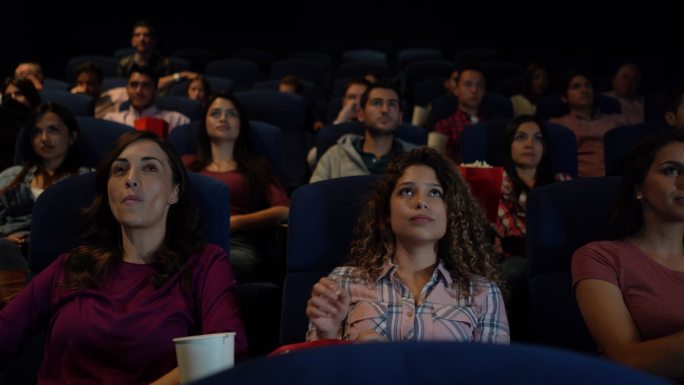 一群一边吃零食一边在电影院看电影的人
