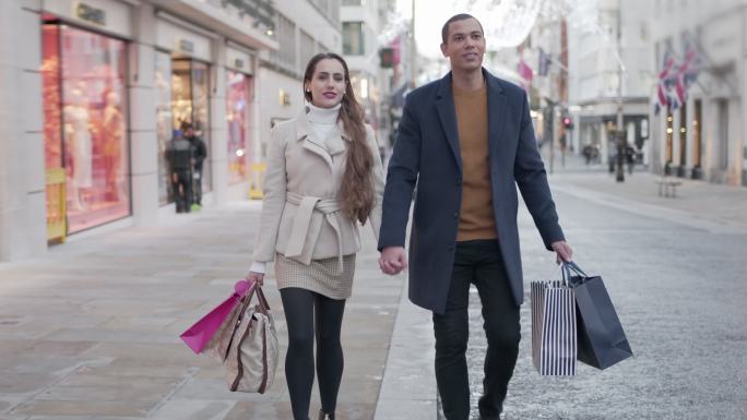 一对年轻夫妇走在城市街道上买圣诞礼物