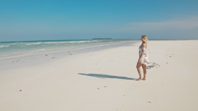 穿着长裙在沙滩上散步女子