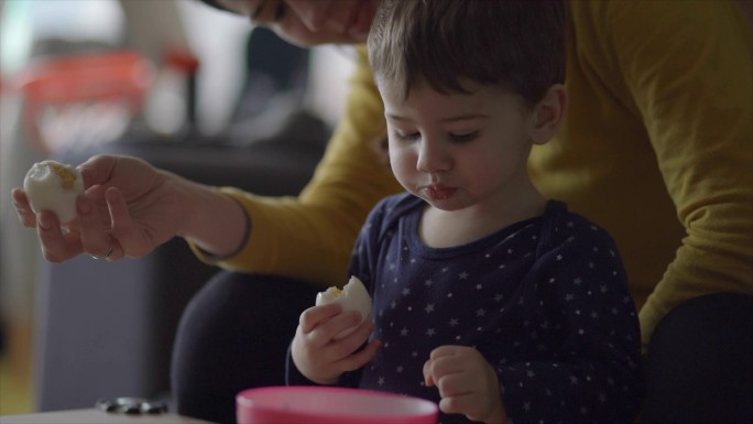 妈妈正在用牛奶和鸡蛋喂她的小男孩