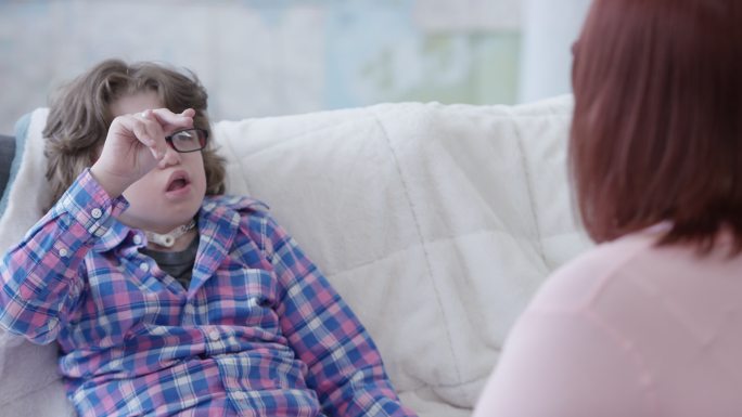 一个残疾的小男孩坐在沙发上