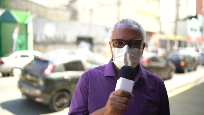 一名戴着面罩的电视记者对着摄像机讲话