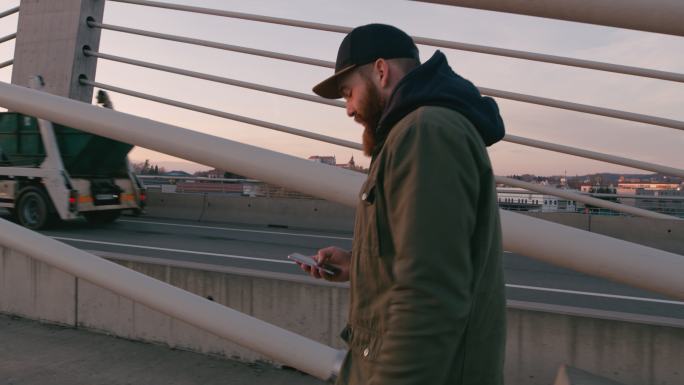 一名男子手持智能手机在桥上行走