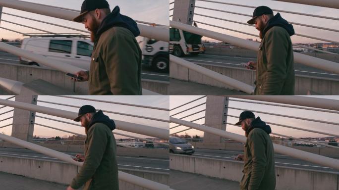 一名男子手持智能手机在桥上行走