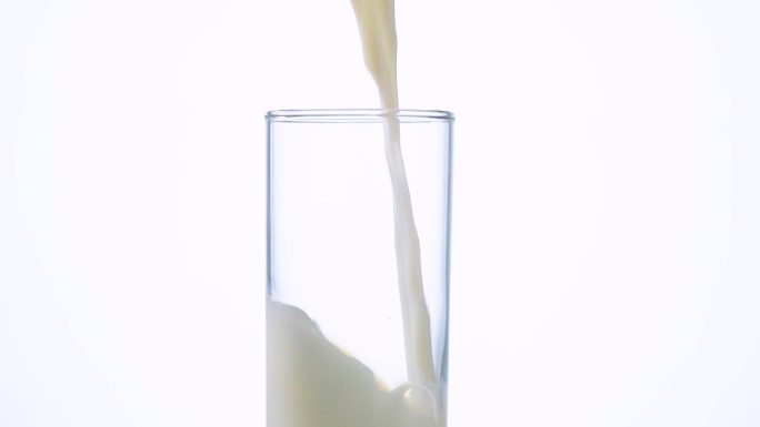 从罐子里把牛奶倒入透明玻璃杯慢镜头