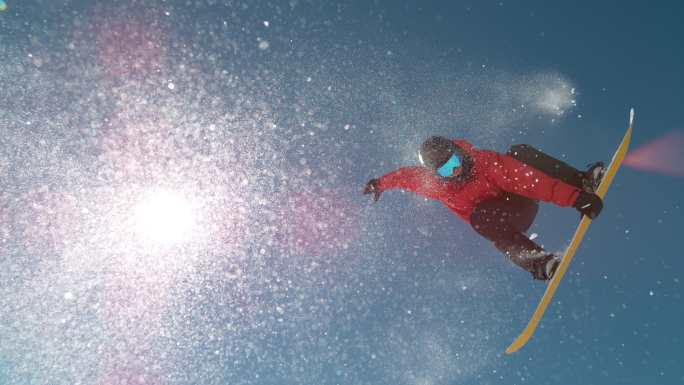 当运动玩滑雪板时，雪花在阳光下闪闪发光。
