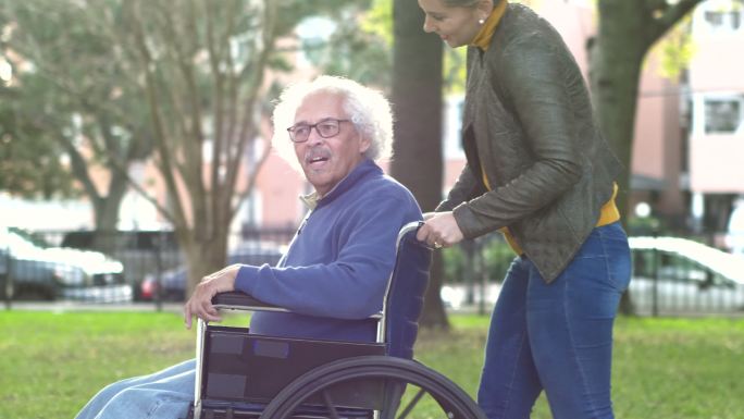 妇女推着轮椅上的年长父亲