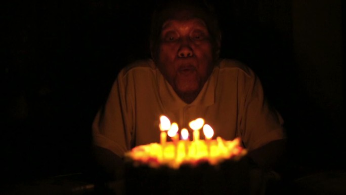 老人吹灭生日蜡烛照明蜡烛