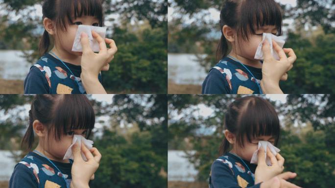 母亲手握纸巾，帮助生病的女儿擦拭和清洁鼻子