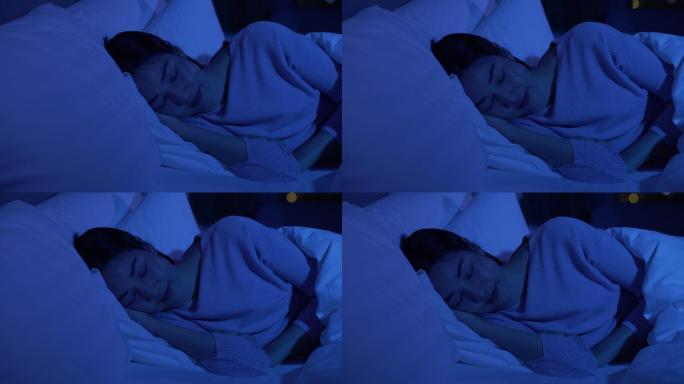 年轻女子晚上闭着眼睛睡在舒适的床上