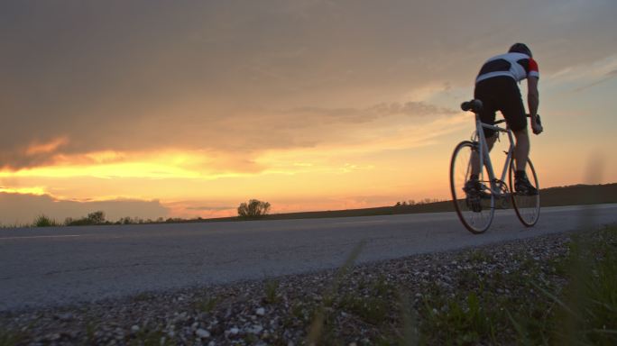 日落时分，骑自行车的人在宁静的乡村道路上