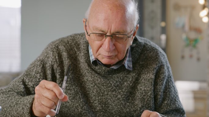一名老年男子坐在家里检查自己的财务状况