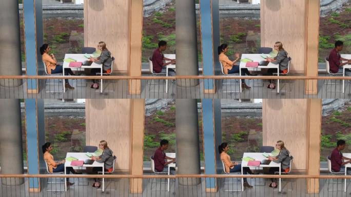 两位女大学生坐在桌旁聊天
