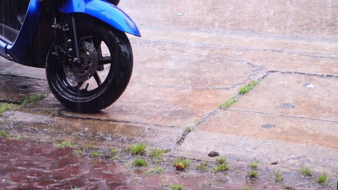 大雨顺着下水道流下来，摩托车停在村子里
