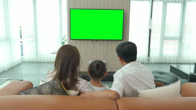 快乐家庭在家里的客厅里坐着看绿屏电视