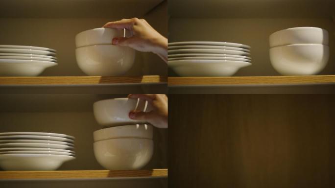 妇女将碗放入一个打开的厨房碗柜