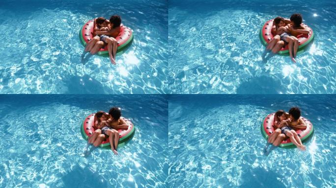 母亲和儿子漂浮在游泳池的游泳圈里