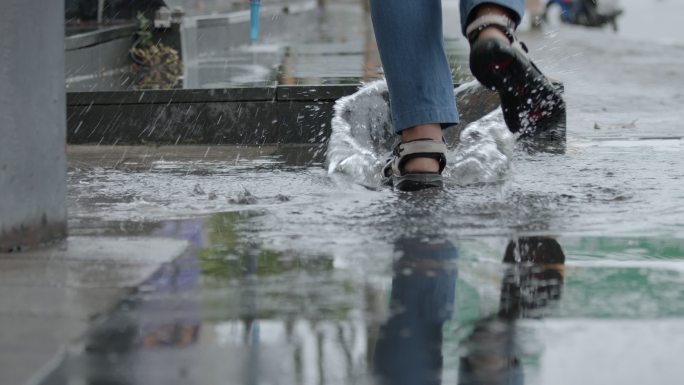 雨天，女人在水坑里跑的慢动作，水花飞溅。